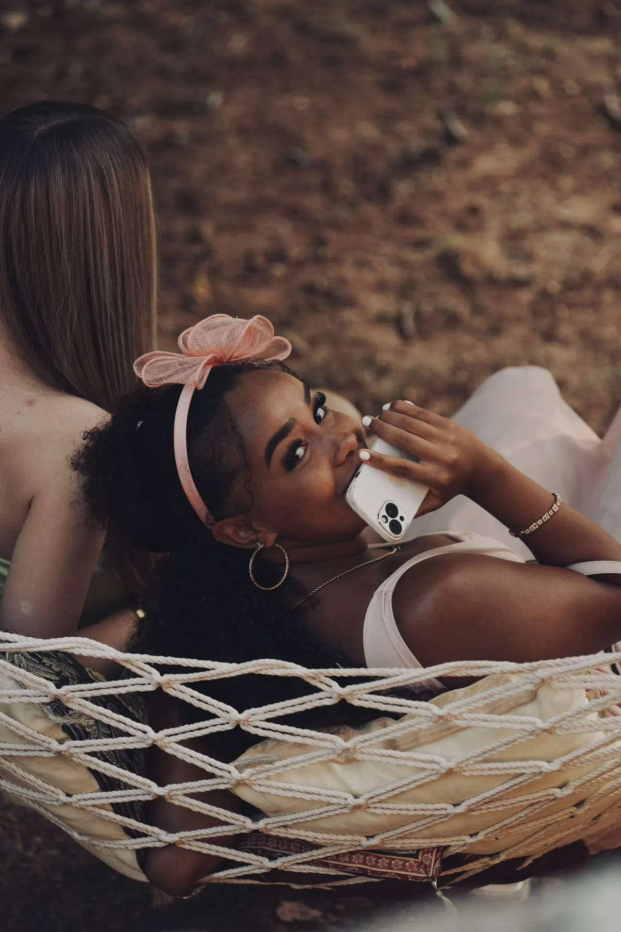 Young flower girl relaxing in rope hammock with pink bow